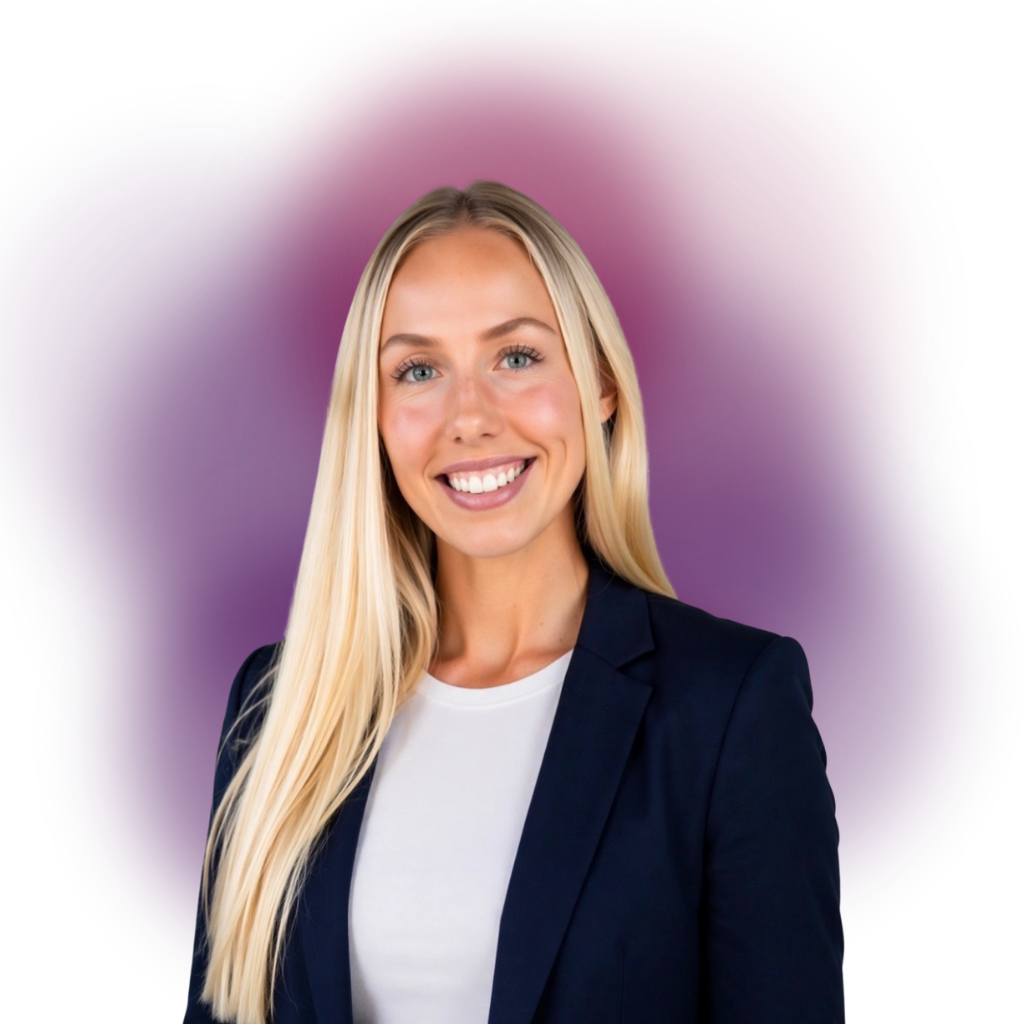 Smiling woman with long blonde hair in a navy blazer and white top, posed for a professional headshot with a purple soft-focus background